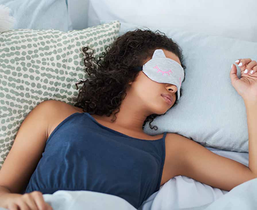 black woman sleeping in bed with a mask